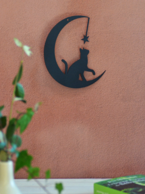 Silhouette en métal peint en noir représentant un chat assis sur un croissant de lune, regardant une étoile. Une décoration poétique et onirique pour sublimer votre intérieur.