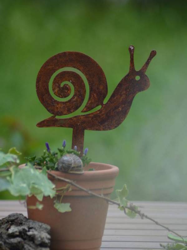 Pic escargot en métal rouillé planté dans un pot de fleurs avec une plante verte